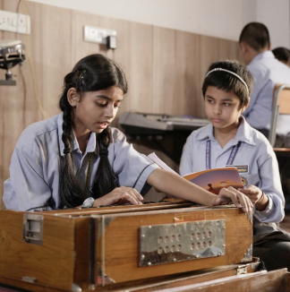 MBIS students participating in a music activity, playing the harmonium with joy and skill
